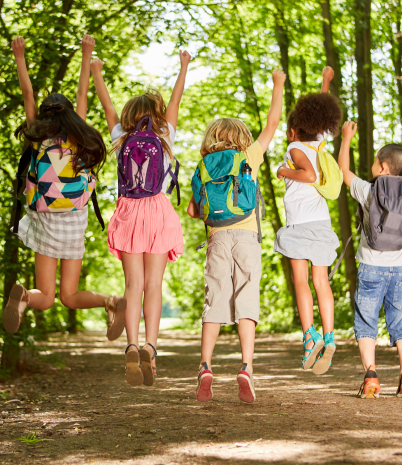 Kids on trail with backpacks jumping in the air